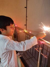 Side view of boy holding lit up at night