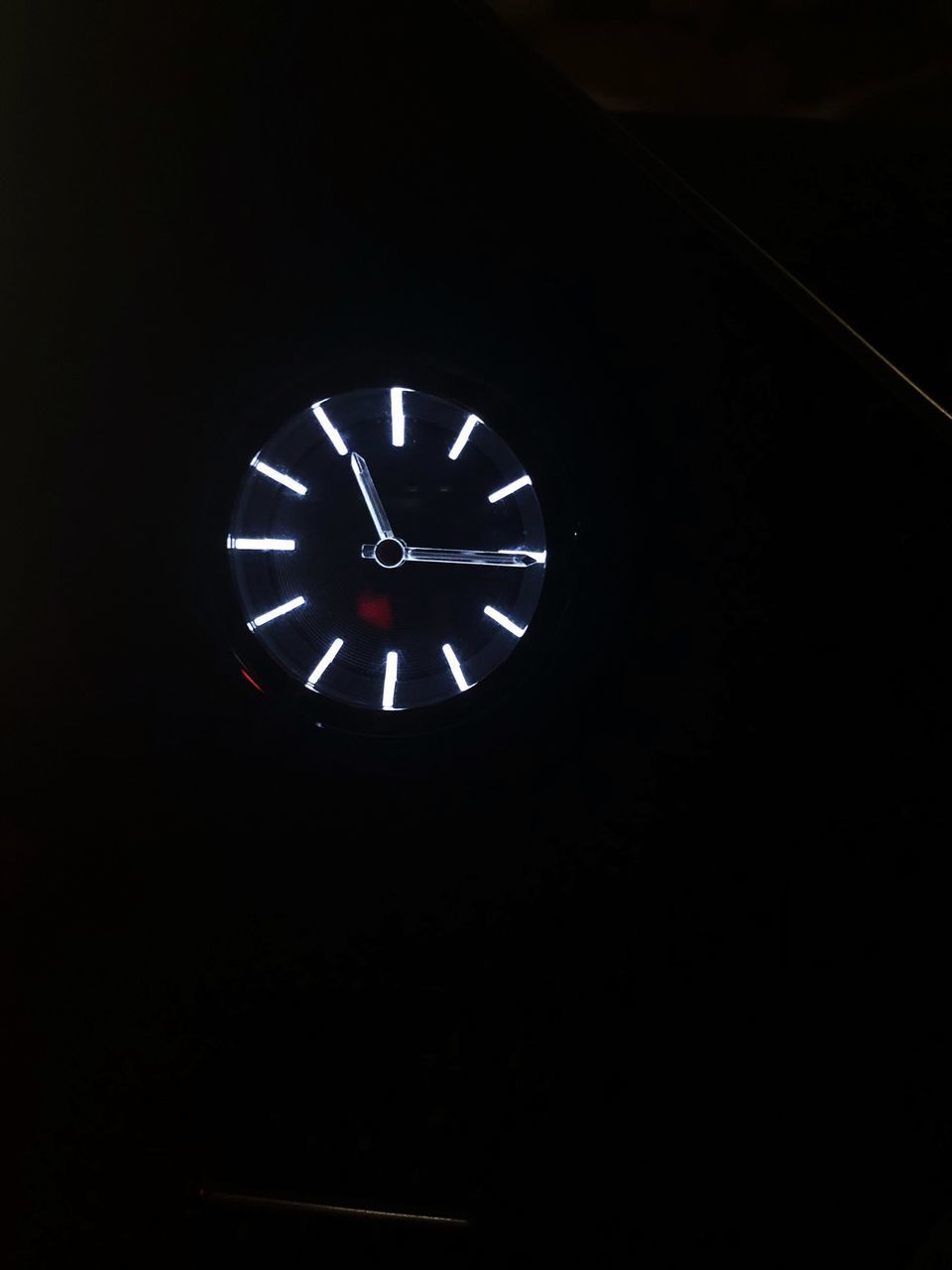 LOW ANGLE VIEW OF CLOCK ON WALL IN DARK