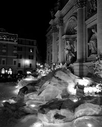 People in illuminated city against sky at night