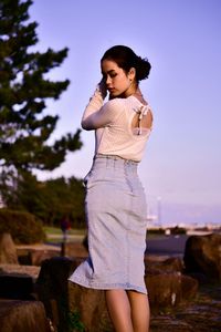 Young woman looking away while standing on land against sky