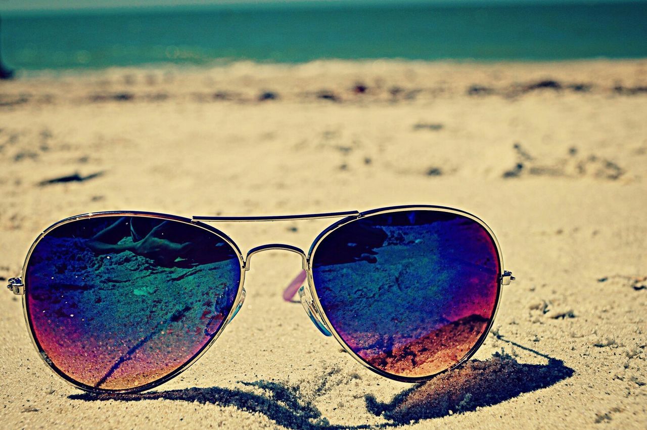 beach, sunglasses, sand, close-up, circle, focus on foreground, blue, shore, day, reflection, sky, outdoors, ball, tranquility, sunlight, nature, geometric shape, field, sport, no people