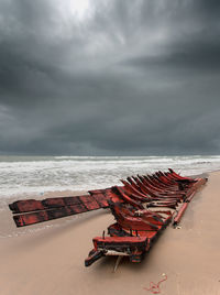 High angle view of abandoned boat at beach against cloudy sky