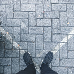 Low section of man standing on cobblestone street