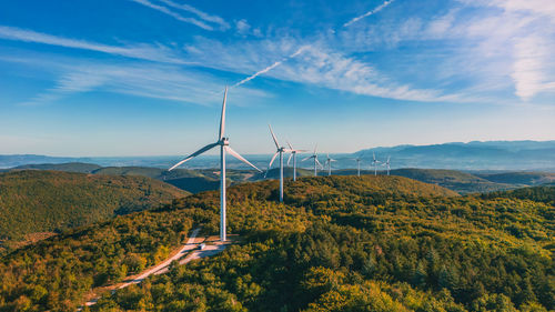 View of a wind farm in a mountainous forest field with mountains in the background