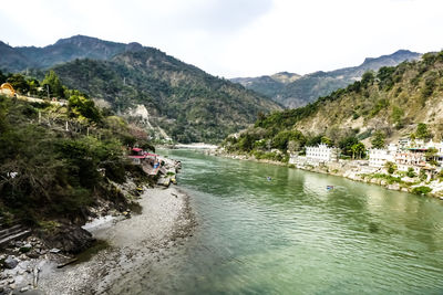 Scenic view of river by mountains against sky