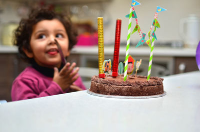 Happy child sitting by cake at home