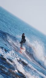 Man surfing in sea against sky