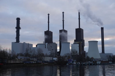 Smoke emitting from factory against sky