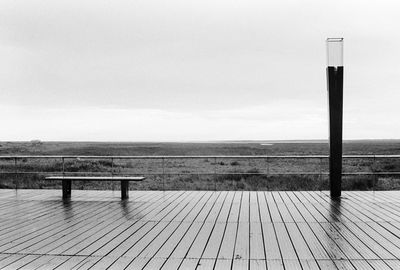 Bench on beach against sky