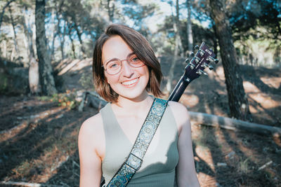 Portrait of young woman standing against trees