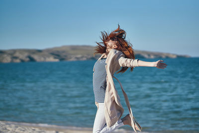 Woman standing at beach against sky