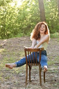 Full length portrait of smiling young woman sitting on chair