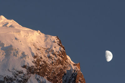 Low angle view of snowcapped mountains against clear sky