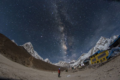 Rear view of man standing on mountain against sky