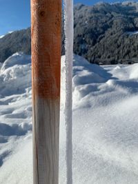 Close-up of wooden post on snow covered land