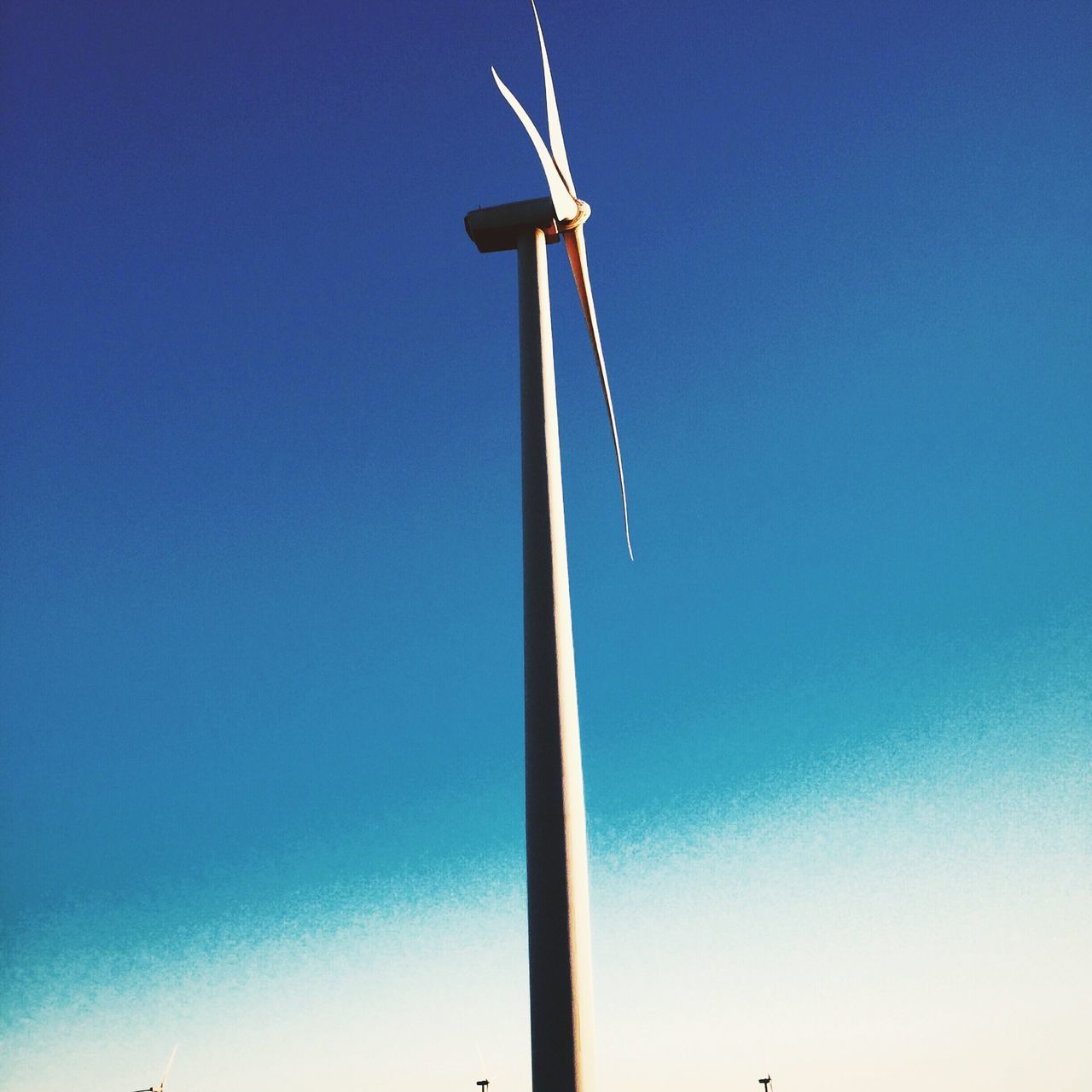 low angle view, clear sky, blue, copy space, wind power, windmill, wind turbine, alternative energy, fuel and power generation, renewable energy, environmental conservation, sky, pole, day, outdoors, no people, technology, nature, vapor trail, wind