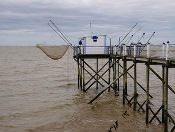 Wooden posts on beach against sky