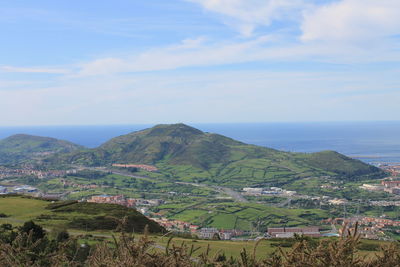 Scenic view of agricultural field by sea against sky