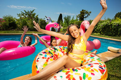 Portrait of smiling young woman sitting on slide while lying on inflatable ring