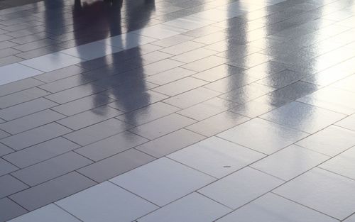 Diffuse reflections of pedestrians walking a marble sidewalk