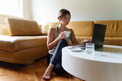 Young woman using mobile phone while sitting on sofa at home