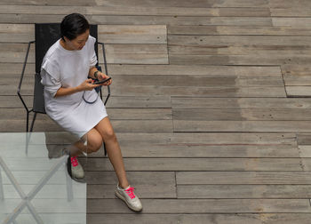 Full length of woman using mobile phone while sitting on floor