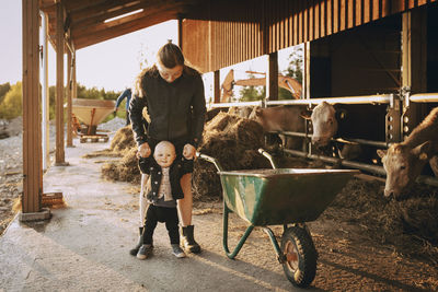 Mother holding hands of son while standing in stable