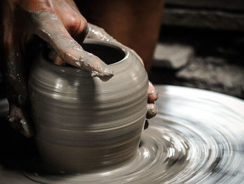 Cropped hands of man molding shape on pottery wheel