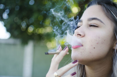 Close-up portrait of woman smoking cigarette outdoors