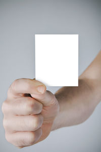 Midsection of person holding paper against white background
