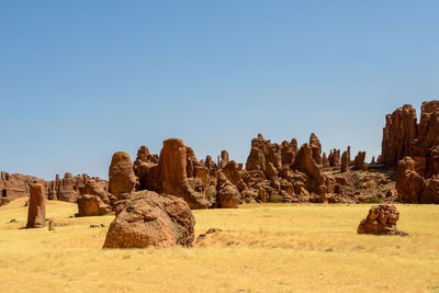 Panoramic view of rocks on landscape against clear blue sky