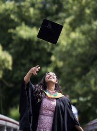 Smiling young woman throwing mortarboard 