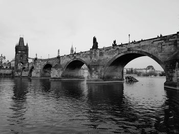 Arch bridge over river against clear sky