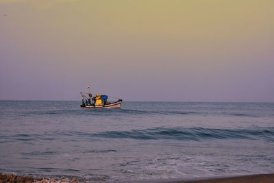 Boat in sea against clear sky during sunset