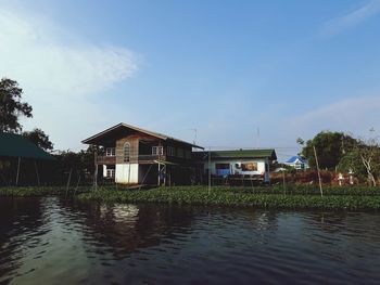 Houses by lake and buildings against sky