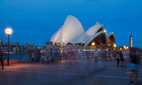 People at illuminated city against sky at night