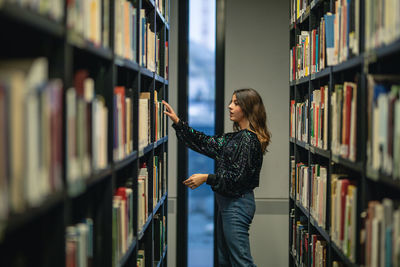 Side view of young woman standing at library