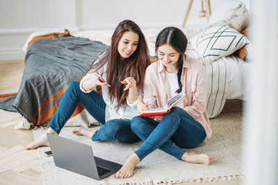 Female friends making diary while sitting at home