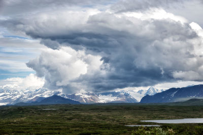 Scenic view of landscape and mountains against cloudy sky