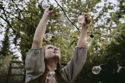 Portrait of woman with bubble against trees