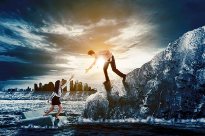 People enjoying in sea against sky during sunset