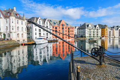 Sailboats moored on river by buildings in city against sky