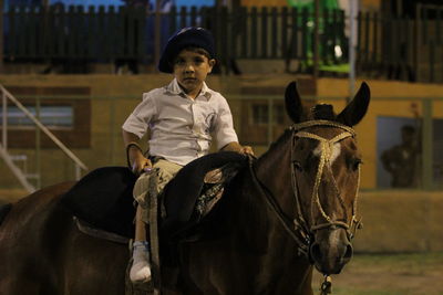 Portrait of boy sitting on horse at night