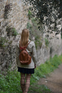 Rear view of woman walking by stone wall