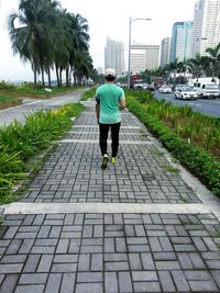 Rear view of man walking on road in city