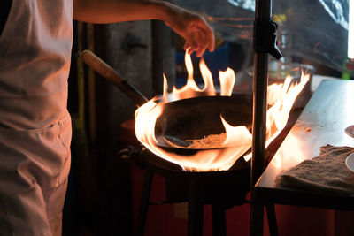 Midsection of chef preparing food in commercial kitchen