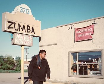 Man standing by sign against sky