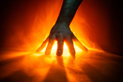 Close-up of hand holding burning at sunset