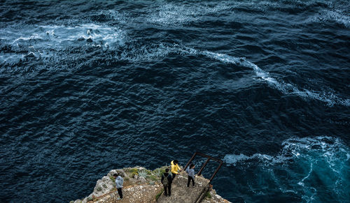 High angle view of people on rock by sea