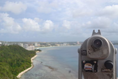 Coin-operated binocular by sea against sky